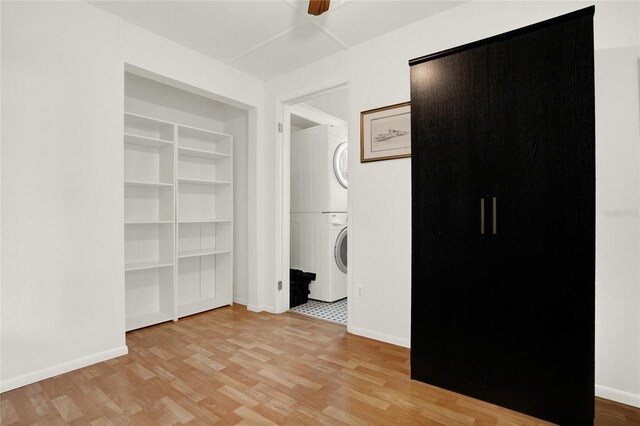 unfurnished bedroom with stacked washer / drying machine, ceiling fan, and light hardwood / wood-style floors