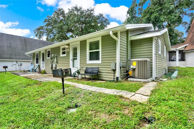 view of front of home featuring a front yard, a patio area, and central AC