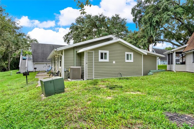 rear view of house with cooling unit and a lawn