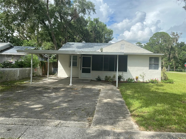 single story home with a sunroom, a front yard, and a carport