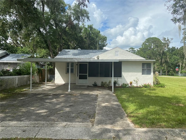 ranch-style home with a sunroom, a front yard, and a carport