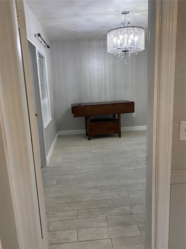 hallway featuring light hardwood / wood-style flooring and a notable chandelier