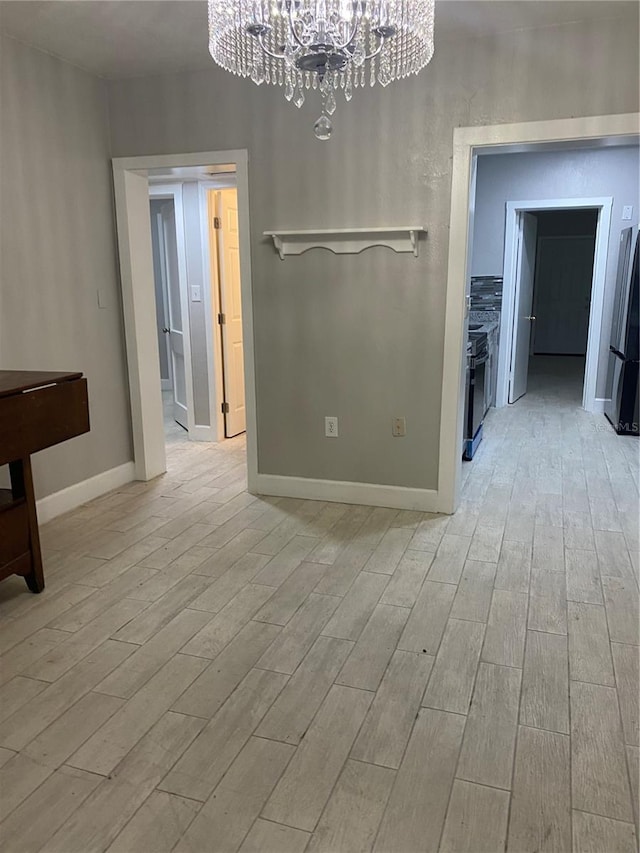 unfurnished dining area featuring an inviting chandelier and light hardwood / wood-style floors