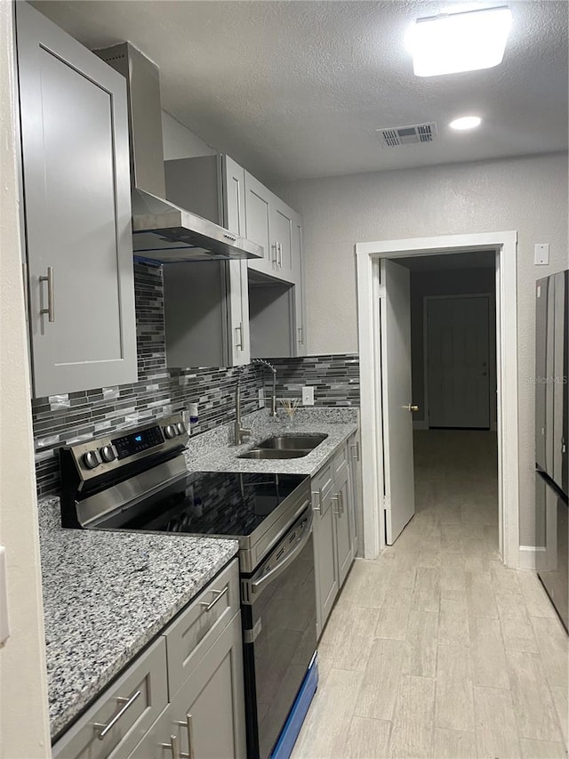 kitchen featuring stainless steel range with electric stovetop, a textured ceiling, sink, and wall chimney range hood