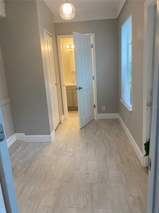 unfurnished bedroom with light wood-type flooring, multiple windows, and crown molding