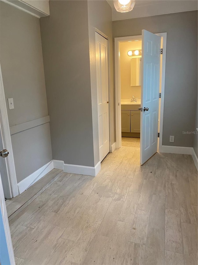 unfurnished bedroom featuring light wood-type flooring, sink, and ensuite bath