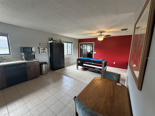 interior space featuring ceiling fan, light tile patterned floors, black dishwasher, and a textured ceiling