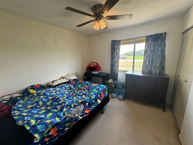 bedroom with a closet, ceiling fan, a textured ceiling, and carpet floors