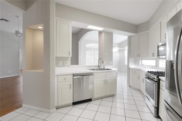 kitchen with ceiling fan, appliances with stainless steel finishes, white cabinetry, light wood-type flooring, and sink