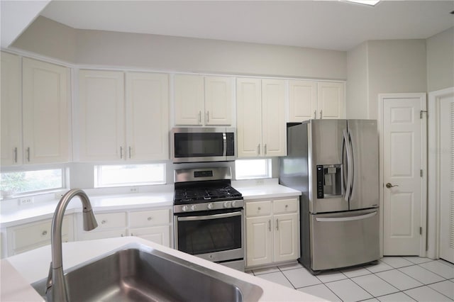 kitchen featuring sink, white cabinetry, stainless steel appliances, and light tile patterned floors