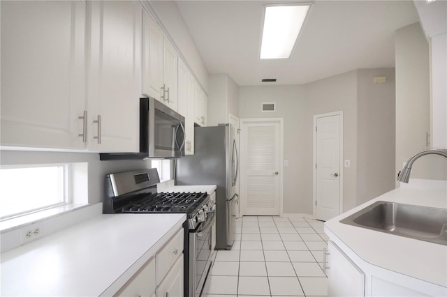 kitchen featuring sink, appliances with stainless steel finishes, white cabinets, and light tile patterned flooring