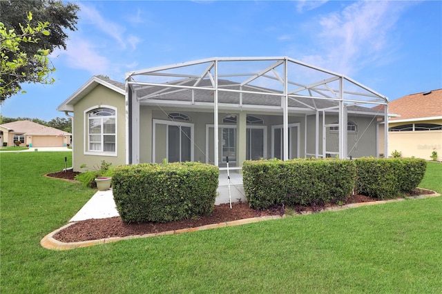 rear view of house with a yard and glass enclosure