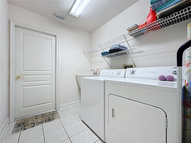 laundry area featuring independent washer and dryer, sink, a textured ceiling, and light tile patterned floors