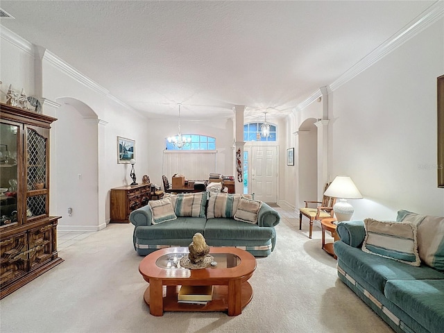 carpeted living room featuring a textured ceiling, ornate columns, a notable chandelier, and ornamental molding