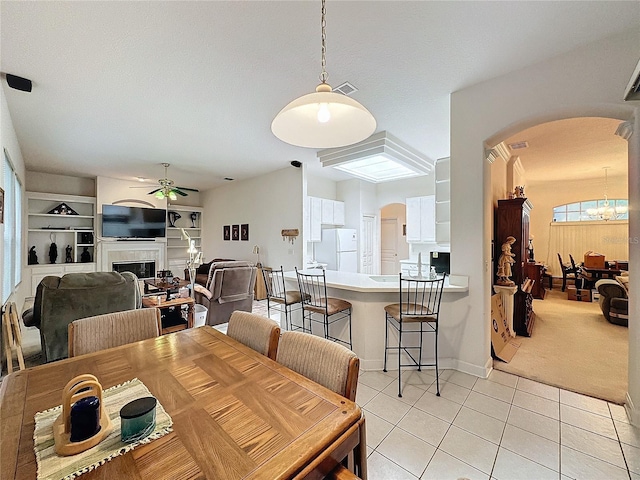 dining area featuring a textured ceiling, light tile patterned flooring, and ceiling fan with notable chandelier