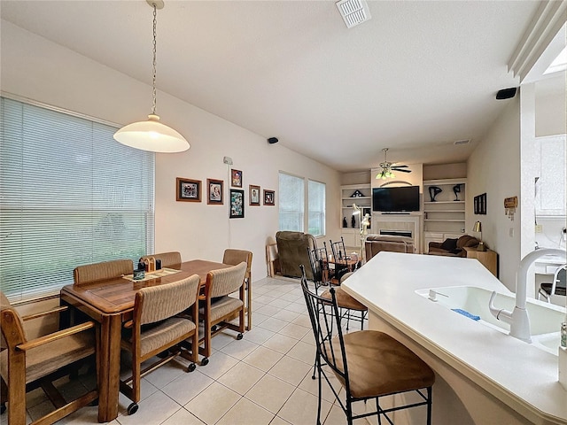 tiled dining space featuring ceiling fan and a fireplace