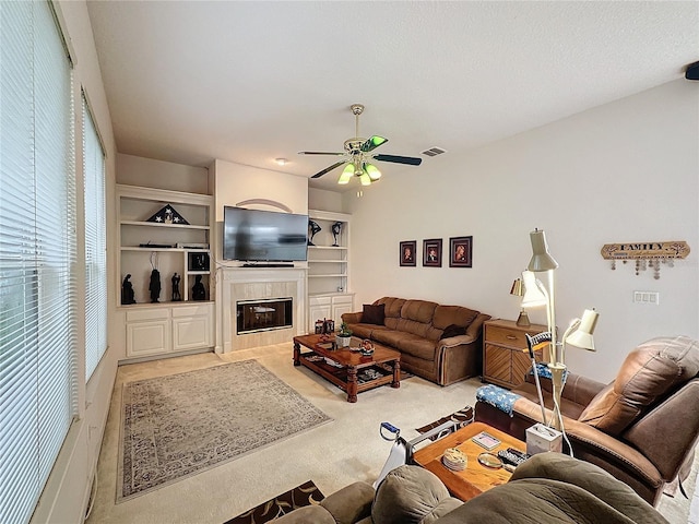 carpeted living room featuring ceiling fan and a tile fireplace