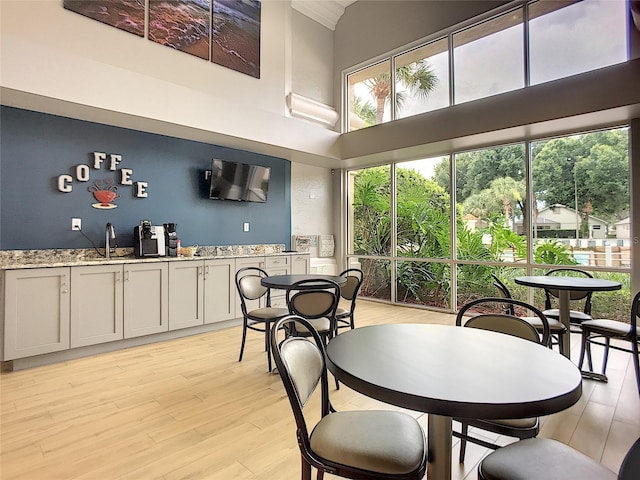 dining area with a high ceiling, light wood-type flooring, and sink