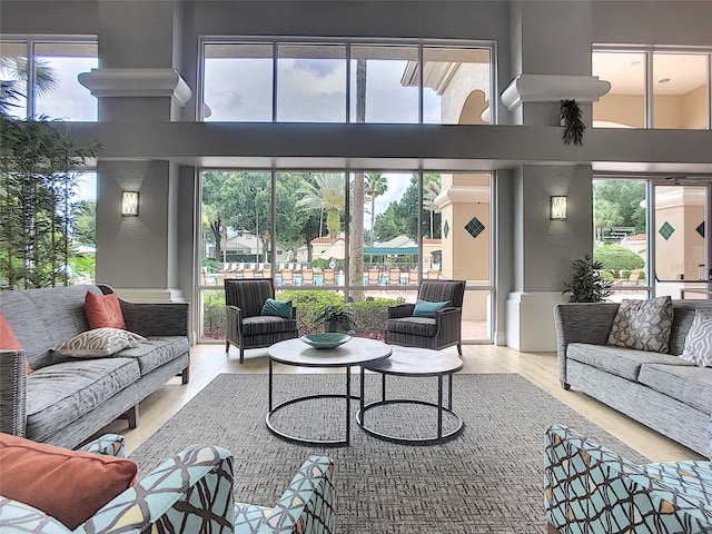 living room featuring plenty of natural light, a high ceiling, and light hardwood / wood-style flooring