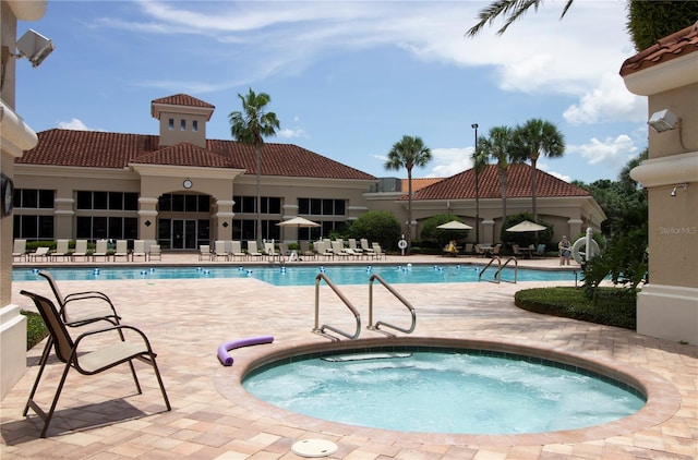 view of swimming pool featuring a hot tub and a patio area