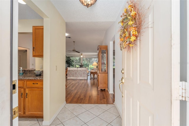 tiled entryway with ceiling fan and a textured ceiling