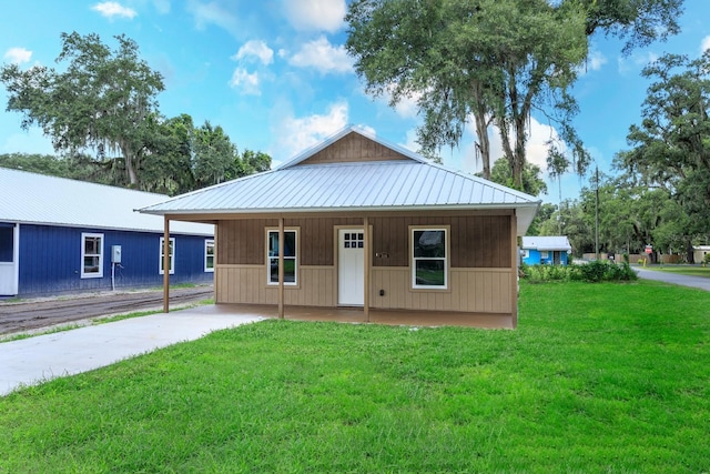 view of front facade featuring a front lawn, driveway, and metal roof