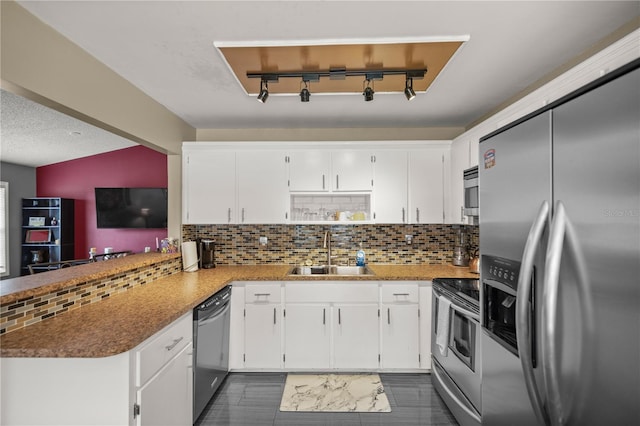 kitchen with tasteful backsplash, stainless steel appliances, kitchen peninsula, sink, and white cabinets