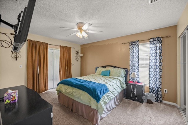 bedroom with a textured ceiling, carpet, and ceiling fan