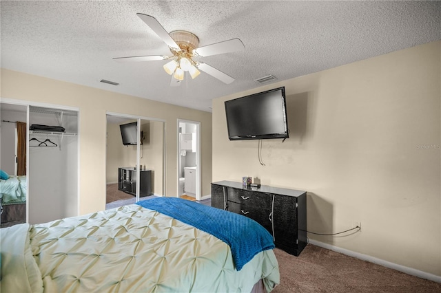 bedroom with a textured ceiling, ceiling fan, carpet floors, and connected bathroom