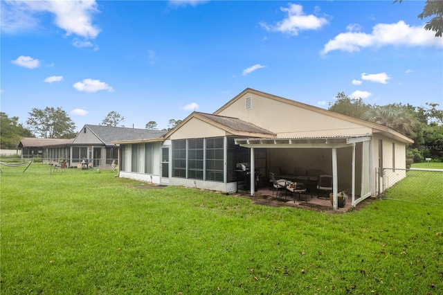 rear view of house with a lawn, a patio, and a sunroom