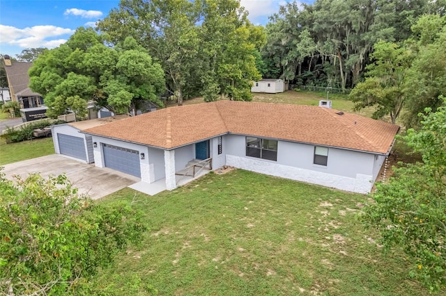 rear view of property with a yard, a garage, and a storage shed