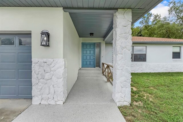 view of exterior entry with a lawn and a garage