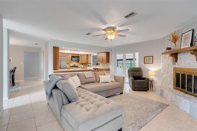 tiled living room featuring a fireplace and ceiling fan