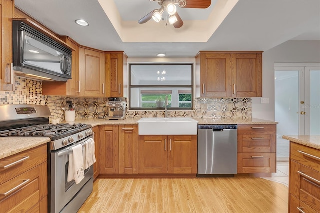 kitchen featuring a tray ceiling, appliances with stainless steel finishes, sink, and ceiling fan