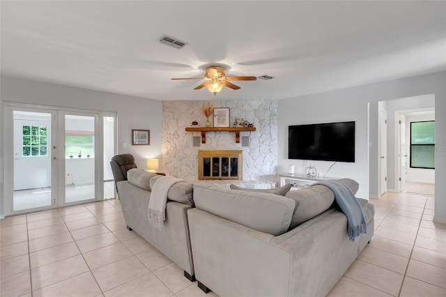 tiled living room with a fireplace and ceiling fan