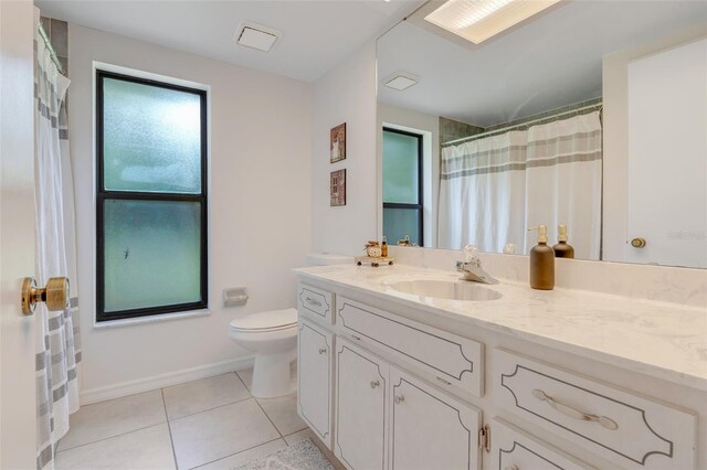 bathroom with vanity, toilet, a healthy amount of sunlight, and tile patterned floors