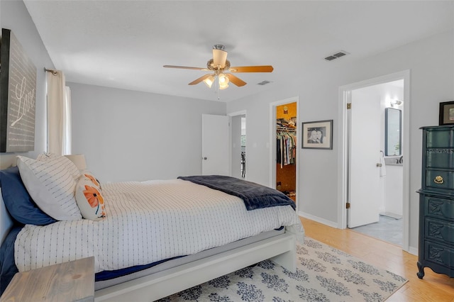 bedroom with light hardwood / wood-style flooring, ensuite bath, ceiling fan, a closet, and a spacious closet