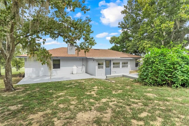 back of property with a lawn and a patio