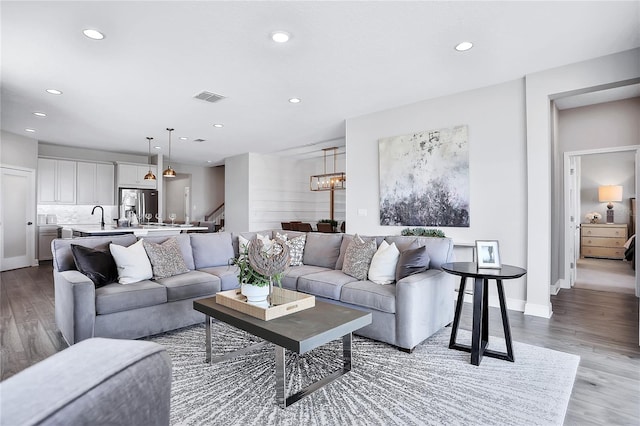 living room with light hardwood / wood-style flooring, sink, and an inviting chandelier