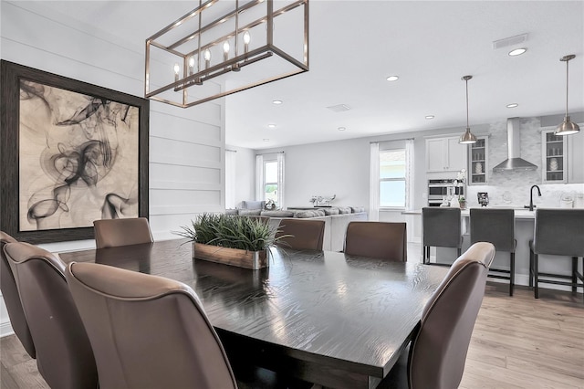 dining room with an inviting chandelier, sink, and light hardwood / wood-style floors