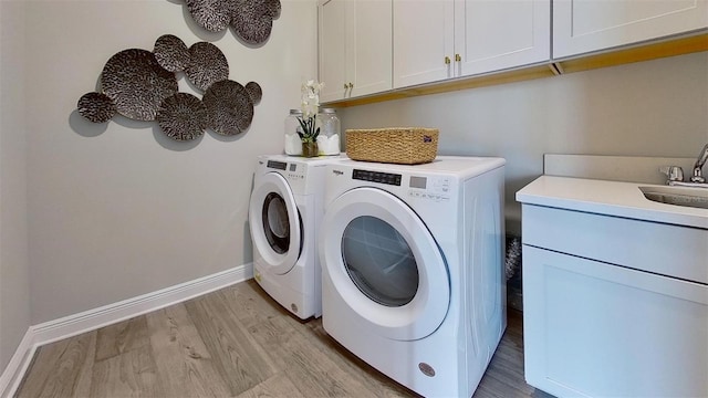 washroom featuring cabinets, washer and clothes dryer, sink, and light hardwood / wood-style floors