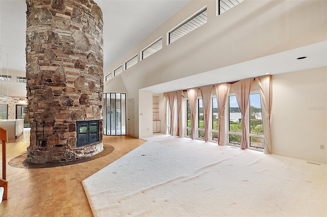 unfurnished living room with a high ceiling and a stone fireplace