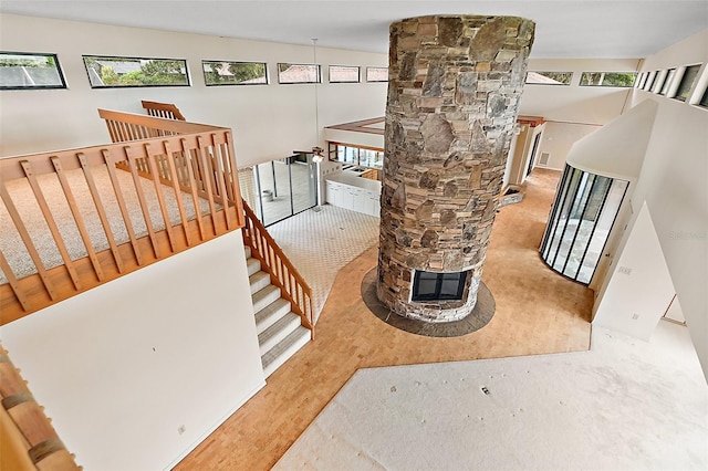 stairway featuring a stone fireplace, vaulted ceiling, and decorative columns