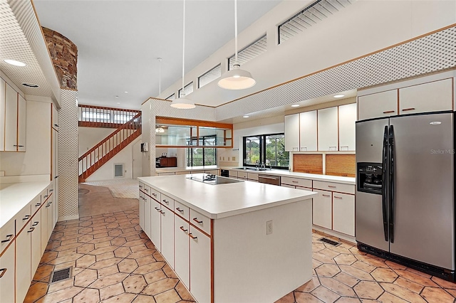 kitchen featuring white cabinets, hanging light fixtures, sink, a kitchen island, and stainless steel appliances