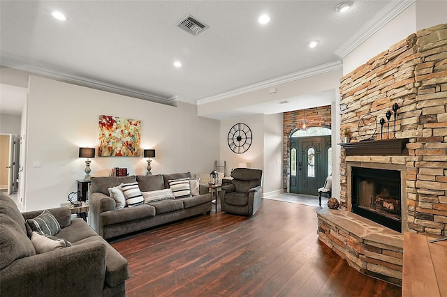 living room with crown molding, a stone fireplace, and dark hardwood / wood-style flooring