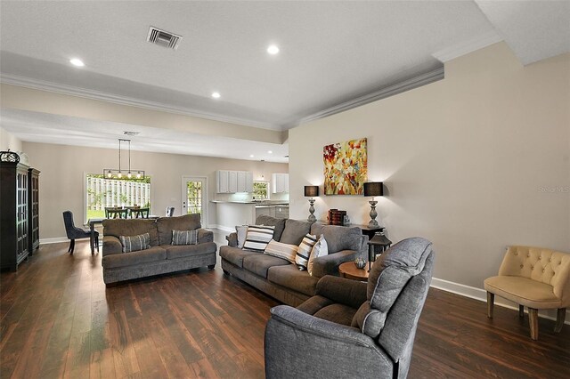 living room featuring crown molding, dark wood-type flooring, and a notable chandelier