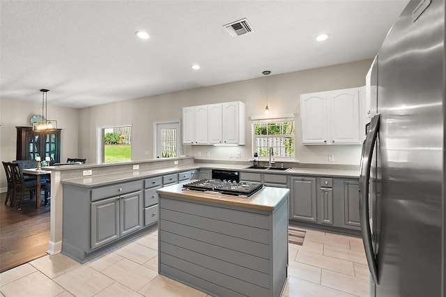 kitchen with gray cabinets, kitchen peninsula, sink, hanging light fixtures, and appliances with stainless steel finishes