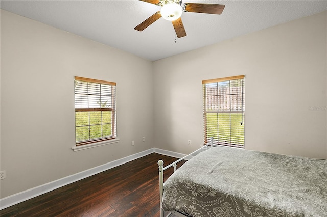 bedroom with dark wood-type flooring, ceiling fan, and a textured ceiling