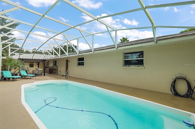 view of pool with an outdoor bar, a patio, and glass enclosure