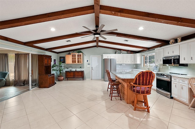 kitchen featuring a kitchen island, appliances with stainless steel finishes, a kitchen breakfast bar, and white cabinetry